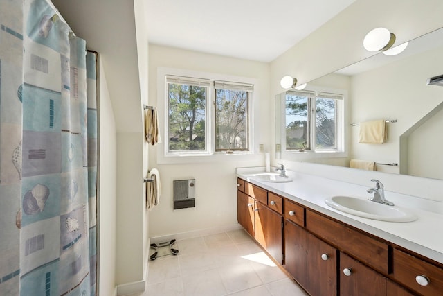 bathroom with baseboards, heating unit, a sink, and double vanity