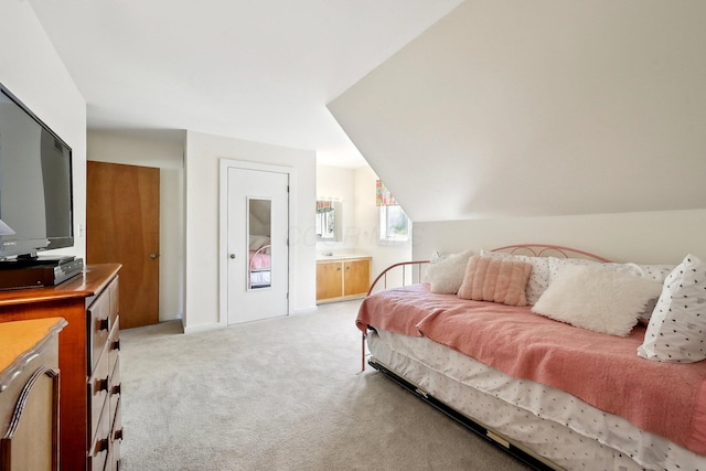 bedroom with vaulted ceiling, ensuite bathroom, and light colored carpet