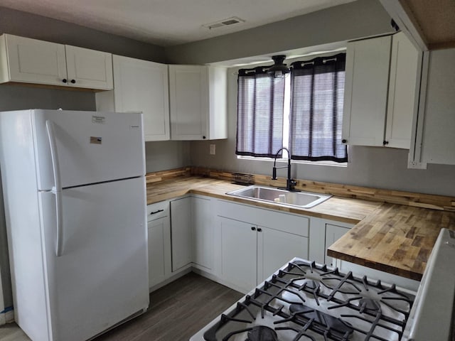 kitchen with visible vents, a sink, freestanding refrigerator, dark wood-style floors, and wood counters