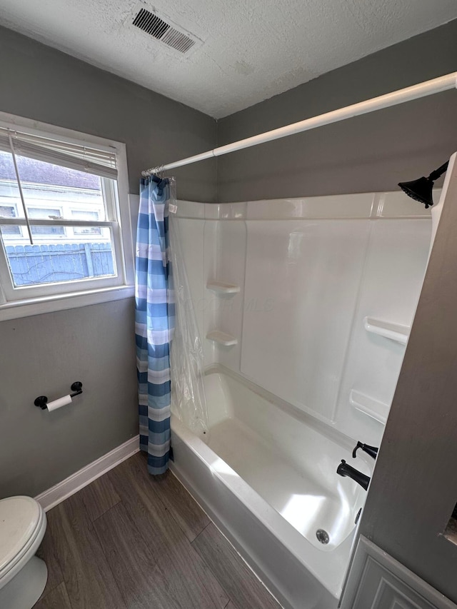 2969 E 11th Ave, Columbus, OH 43219 - bathroom featuring toilet, wood finished floors, shower / tub combo with curtain, a textured ceiling, and baseboards
