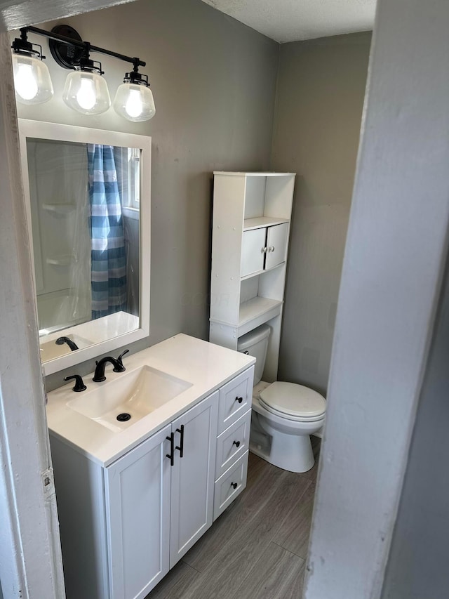 2969 E 11th Ave, Columbus, OH 43219 - bathroom featuring vanity, toilet, a shower with shower curtain, and wood finished floors