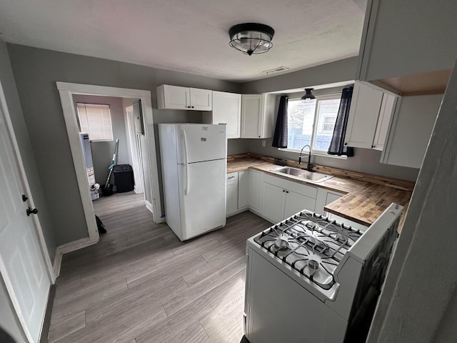 2969 E 11th Ave, Columbus, OH 43219 - kitchen with freestanding refrigerator, gas stove, a sink, light wood-style flooring, and white cabinetry