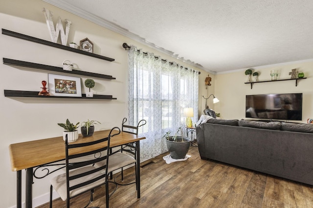 living room with wood finished floors, a textured ceiling, and ornamental molding