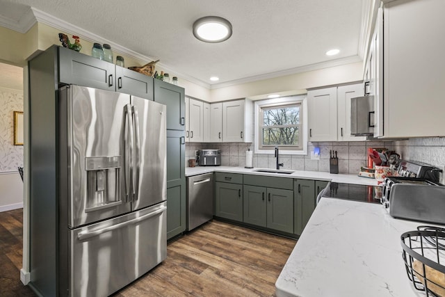 kitchen with stainless steel appliances, a sink, dark wood-type flooring, light stone countertops, and crown molding