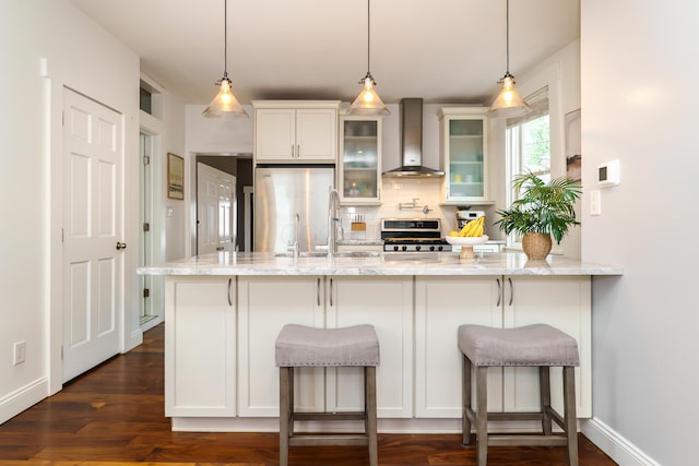 129 Jackson St, Columbus, OH 43206 - kitchen with wall chimney exhaust hood, stainless steel appliances, decorative backsplash, glass insert cabinets, and light stone counters