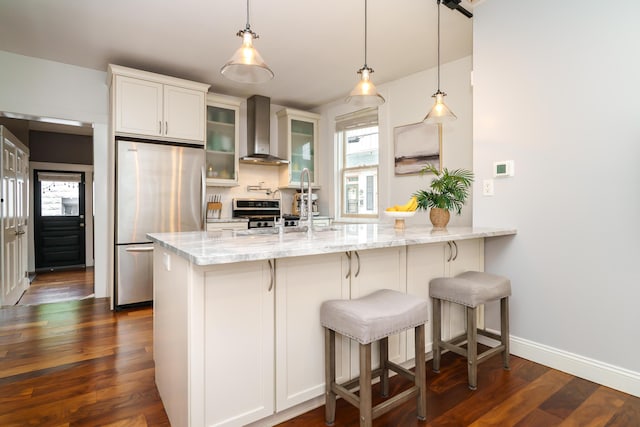 129 Jackson St, Columbus, OH 43206 - kitchen featuring wall chimney range hood, freestanding refrigerator, light stone counters, glass insert cabinets, and dark wood-style floors