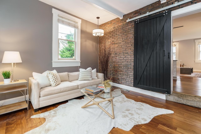 129 Jackson St, Columbus, OH 43206 - living room with a barn door, brick wall, wood finished floors, and baseboards