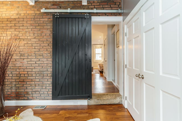 129 Jackson St, Columbus, OH 43206 - corridor with a barn door, brick wall, wood finished floors, and baseboards
