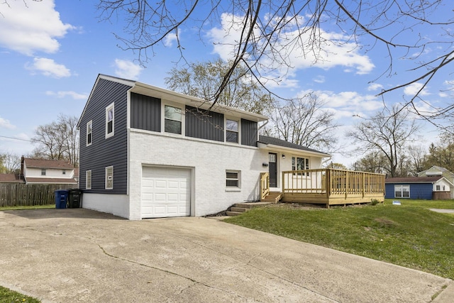 exterior space with concrete driveway, a lawn, a deck, a garage, and brick siding