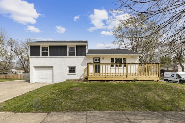 tri-level home featuring a garage, a front lawn, driveway, brick siding, and a deck