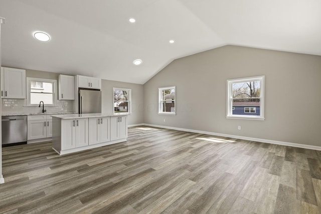 kitchen with light countertops, a kitchen island, appliances with stainless steel finishes, open floor plan, and white cabinetry