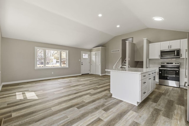 kitchen featuring light wood-style floors, stainless steel appliances, white cabinets, lofted ceiling, and visible vents