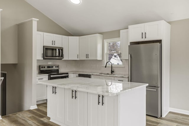 kitchen with a center island, a sink, decorative backsplash, light wood-style flooring, and appliances with stainless steel finishes