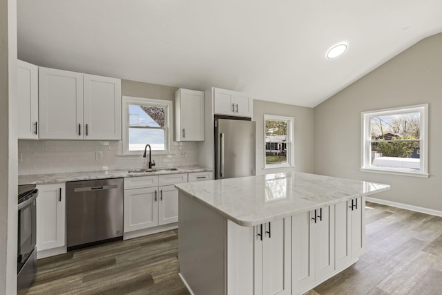 kitchen featuring vaulted ceiling, dark wood-style flooring, stainless steel appliances, and a sink