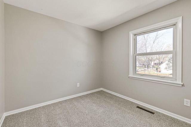 empty room with carpet, visible vents, and baseboards