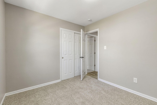 unfurnished bedroom featuring carpet floors, a closet, and baseboards