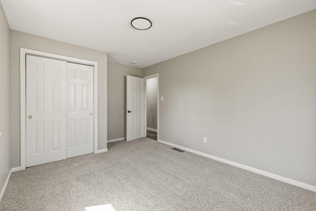 unfurnished bedroom featuring visible vents, baseboards, carpet floors, and a closet