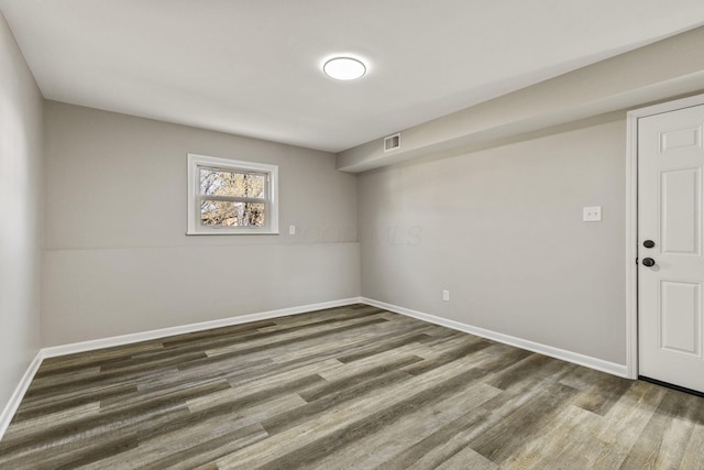 below grade area with baseboards, wood finished floors, and visible vents