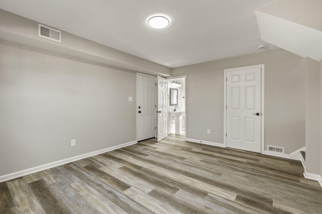 interior space featuring wood finished floors, visible vents, baseboards, and stairway
