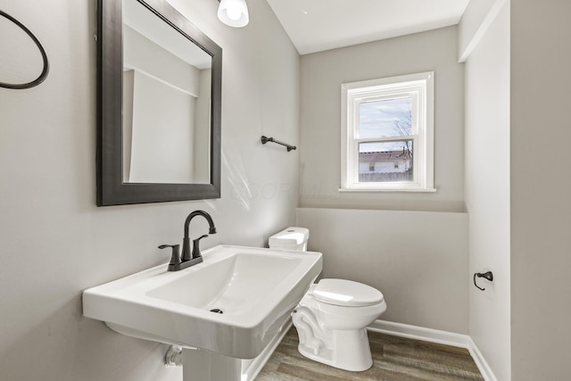 bathroom featuring a sink, toilet, wood finished floors, and baseboards