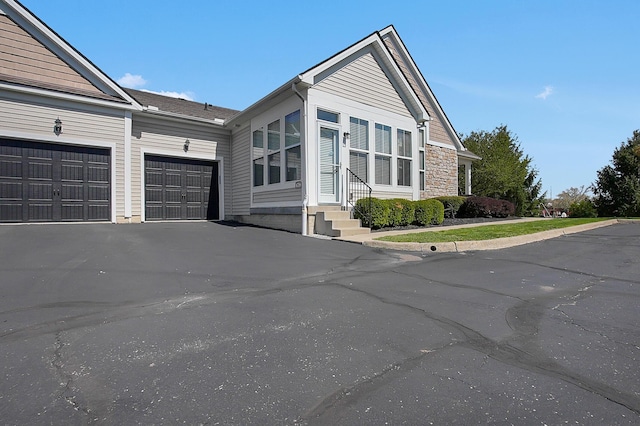 view of front of house featuring entry steps, an attached garage, and driveway