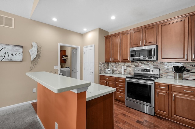 kitchen featuring washing machine and clothes dryer, backsplash, light countertops, and appliances with stainless steel finishes