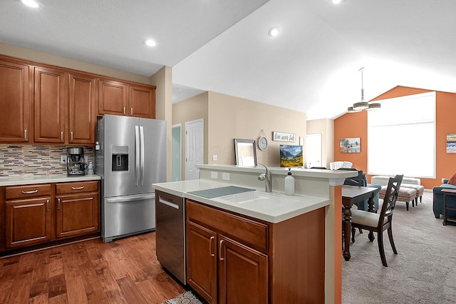 kitchen with vaulted ceiling, a sink, stainless steel appliances, a center island with sink, and light countertops