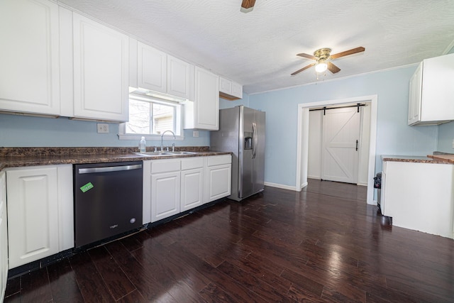 kitchen with stainless steel appliances, white cabinetry, ceiling fan, and a barn door