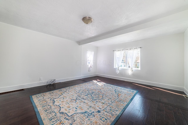 spare room featuring wood-type flooring, baseboards, and a textured ceiling