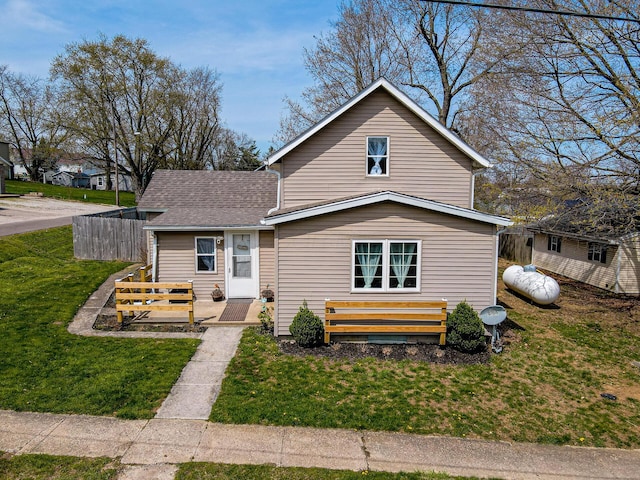 traditional-style house featuring a front lawn and a shingled roof