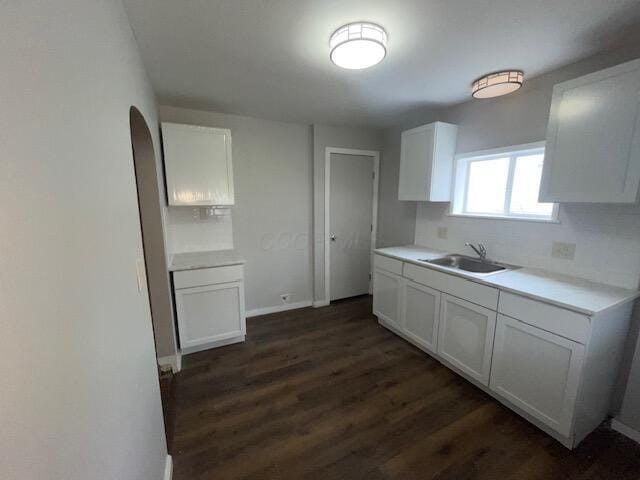 847 S Eureka Ave, Columbus, OH 43204 - kitchen with white cabinets, light countertops, a sink, baseboards, and dark wood-style flooring