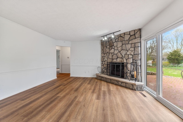 3318 Darbyshire Dr, Hilliard, OH 43026 - unfurnished living room featuring track lighting, wood finished floors, visible vents, a stone fireplace, and baseboards