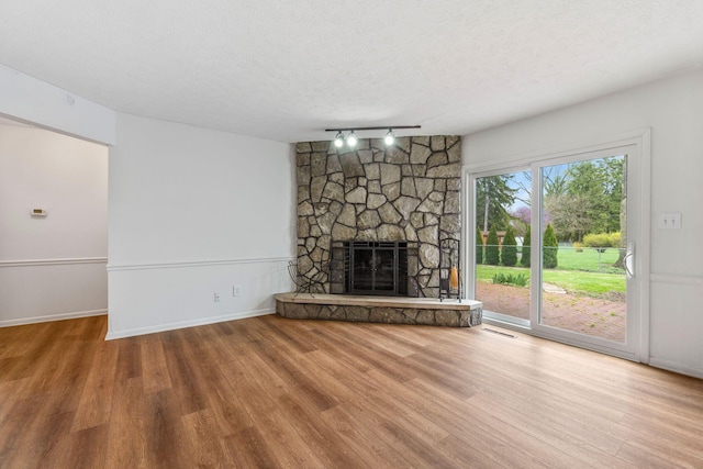 3318 Darbyshire Dr, Hilliard, OH 43026 - unfurnished living room featuring a stone fireplace, wood finished floors, a textured ceiling, and rail lighting