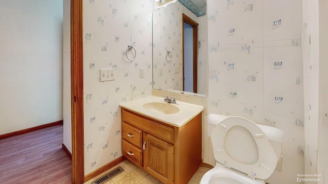 bathroom featuring toilet, baseboards, visible vents, wood finished floors, and vanity