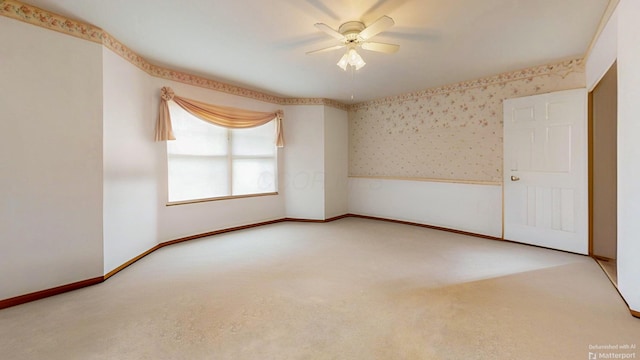 spare room with wallpapered walls, carpet flooring, a ceiling fan, and baseboards