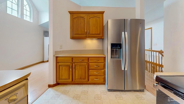 kitchen featuring brown cabinetry, baseboards, stainless steel fridge with ice dispenser, and light countertops