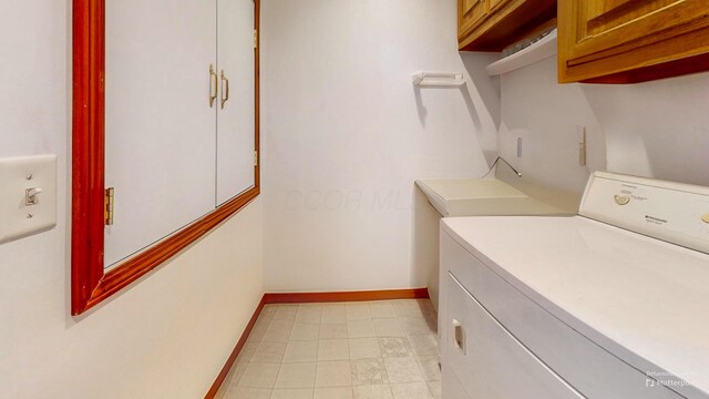 laundry area with baseboards, cabinet space, and washer / dryer