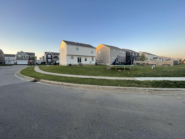 view of front facade with a front lawn, a residential view, and a trampoline