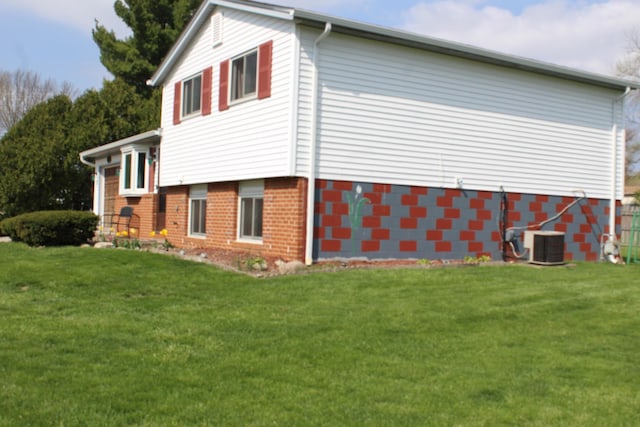 view of property exterior featuring brick siding, a yard, and central air condition unit