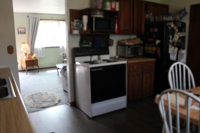 kitchen featuring a sink, dark wood-type flooring, and black appliances