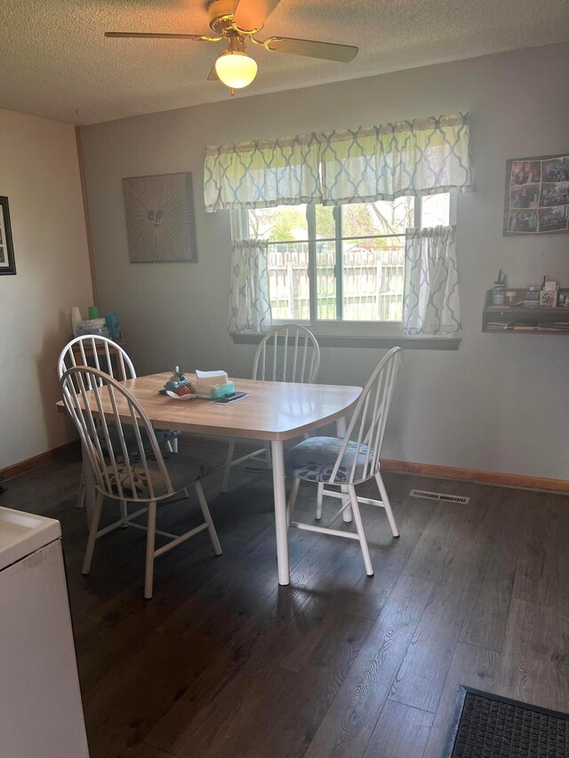 dining area featuring wood finished floors, visible vents, a ceiling fan, baseboards, and a textured ceiling