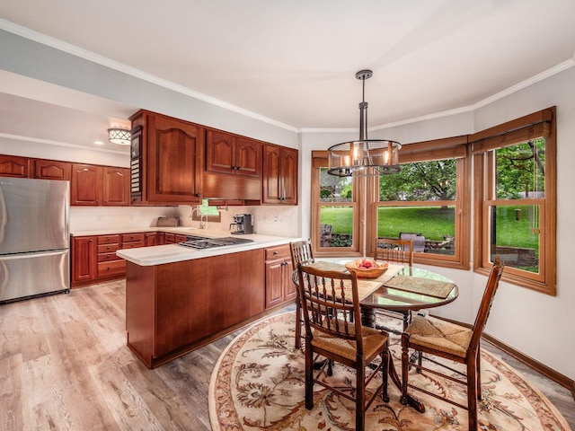 4159 Rowanne Rd, Columbus, OH 43214 - kitchen with stainless steel appliances, a peninsula, light countertops, light wood-style flooring, and a chandelier