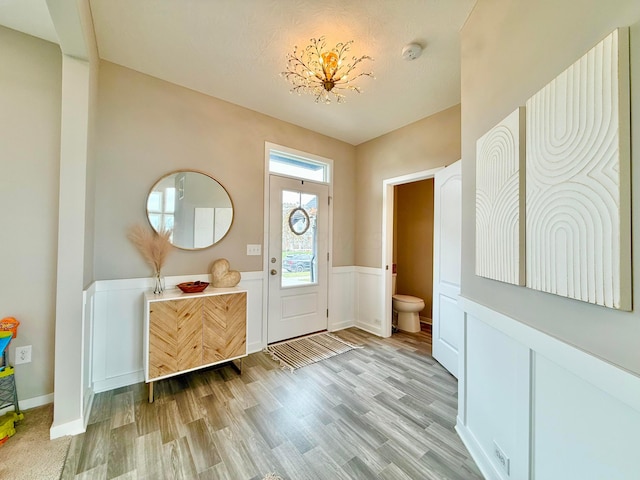 foyer entrance featuring light wood-style floors and a wainscoted wall