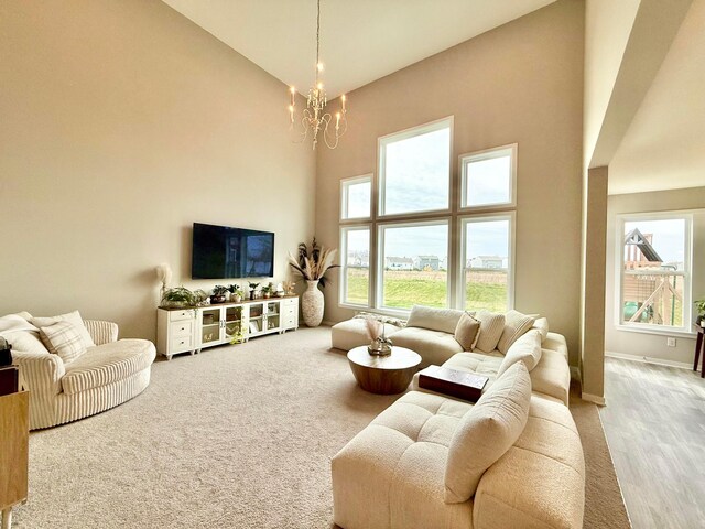 living room featuring high vaulted ceiling, an inviting chandelier, carpet floors, and baseboards