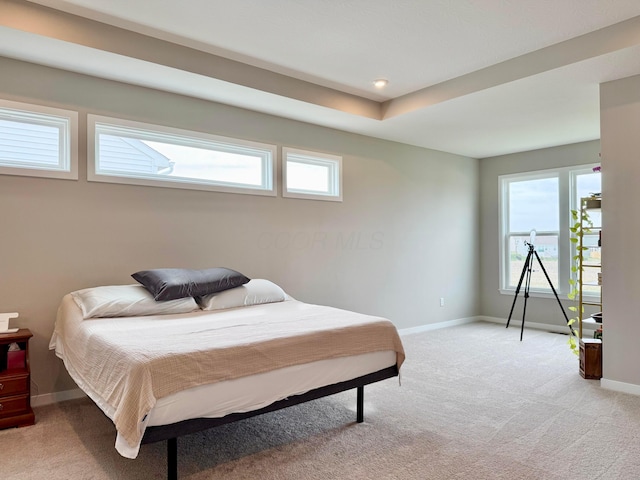 bedroom with baseboards, light colored carpet, and multiple windows