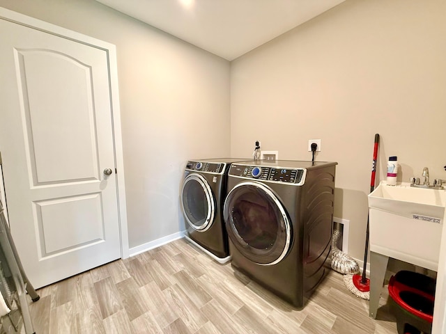 laundry room with baseboards, washer and clothes dryer, laundry area, and light wood-style flooring