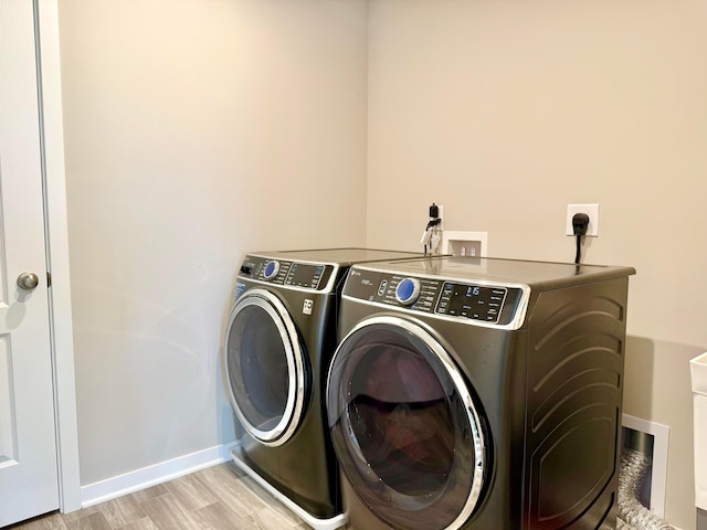 laundry room featuring washer and dryer, baseboards, laundry area, and light wood-type flooring
