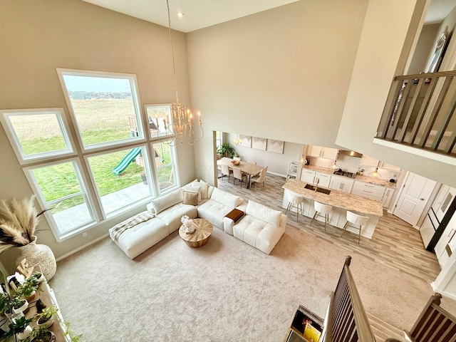 living room with light colored carpet, a wealth of natural light, a chandelier, and a towering ceiling