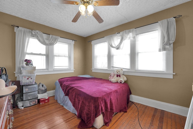 bedroom with wood-type flooring, a textured ceiling, a ceiling fan, and baseboards