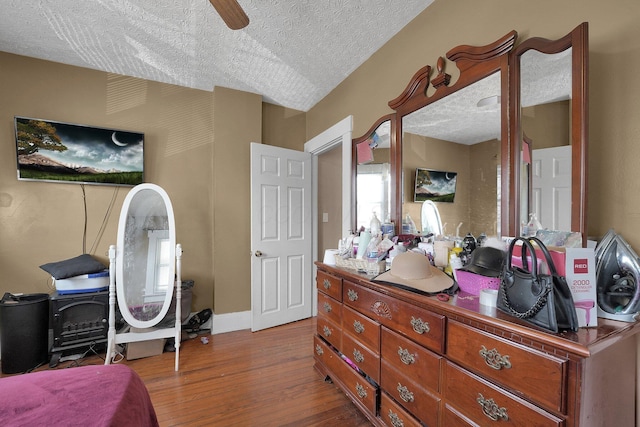 bedroom with baseboards, a ceiling fan, wood finished floors, and a textured ceiling